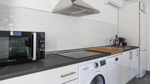 Une cuisine moderne équipée d’un four à micro-ondes encastré, d’un lave-linge et d’une hotte de cuisine en acier inoxydable.