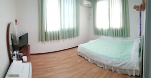 Una camera d'albergo con un letto, una TV, uno specchio e un pavimento in legno.