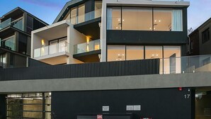 A modern multi-story building with balconies, large windows, and a flat roof.