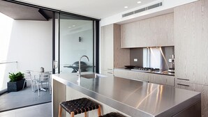 A modern kitchen with a large island, stainless steel appliances, and light wood cabinetry.
