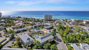 Luftaufnahme eines Küstenresorts mit mehreren Gebäuden, blauem Himmel und dem Meer im Hintergrund.