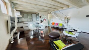 A modern living room with a dining area, a kitchen, and a staircase leading to an upper level. - Arena Deluxe - Duplex apartment with Arena view (Verona)