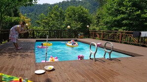 Une terrasse en bois avec une piscine, des jeux gonflables et un espace de jeux pour enfants.