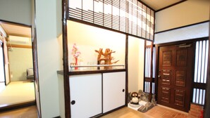 A traditional Japanese interior with sliding doors, a wooden floor, and a small statue. - Mahoroba (Motobu)