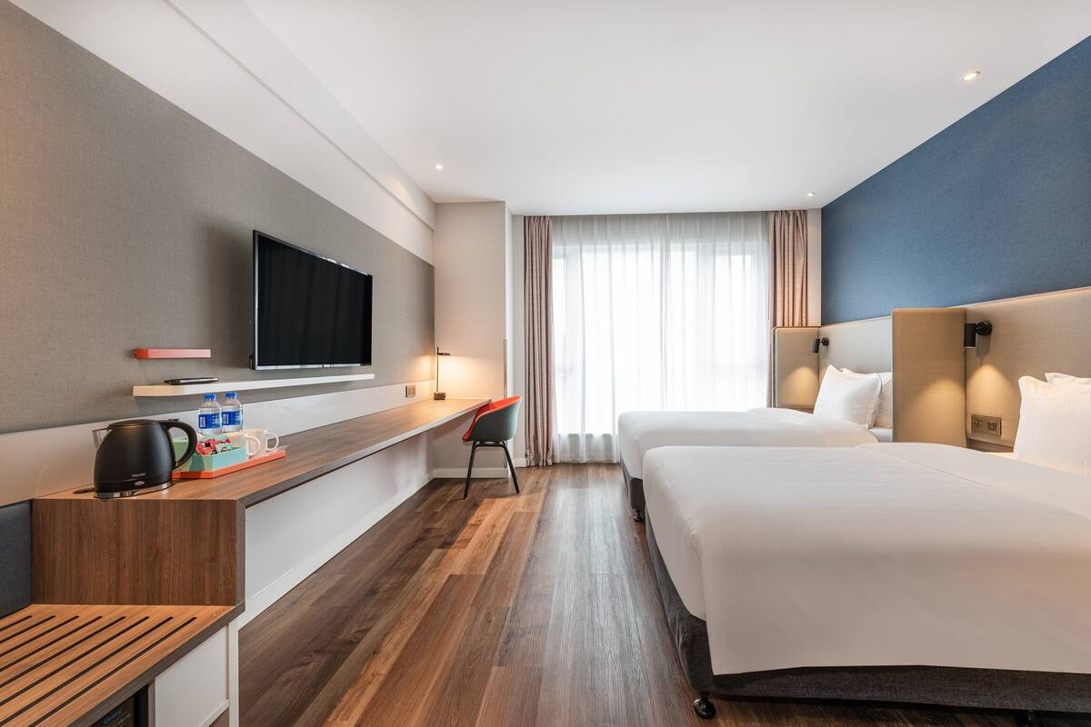 Une chambre d’hôtel avec un grand lit, un bureau doté d’un téléviseur à écran plat, une machine à café et une chaise.