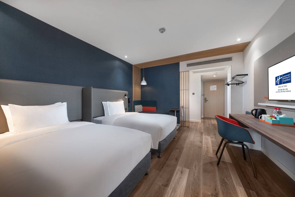 Une chambre d’hôtel avec deux lits, un bureau et une chaise.