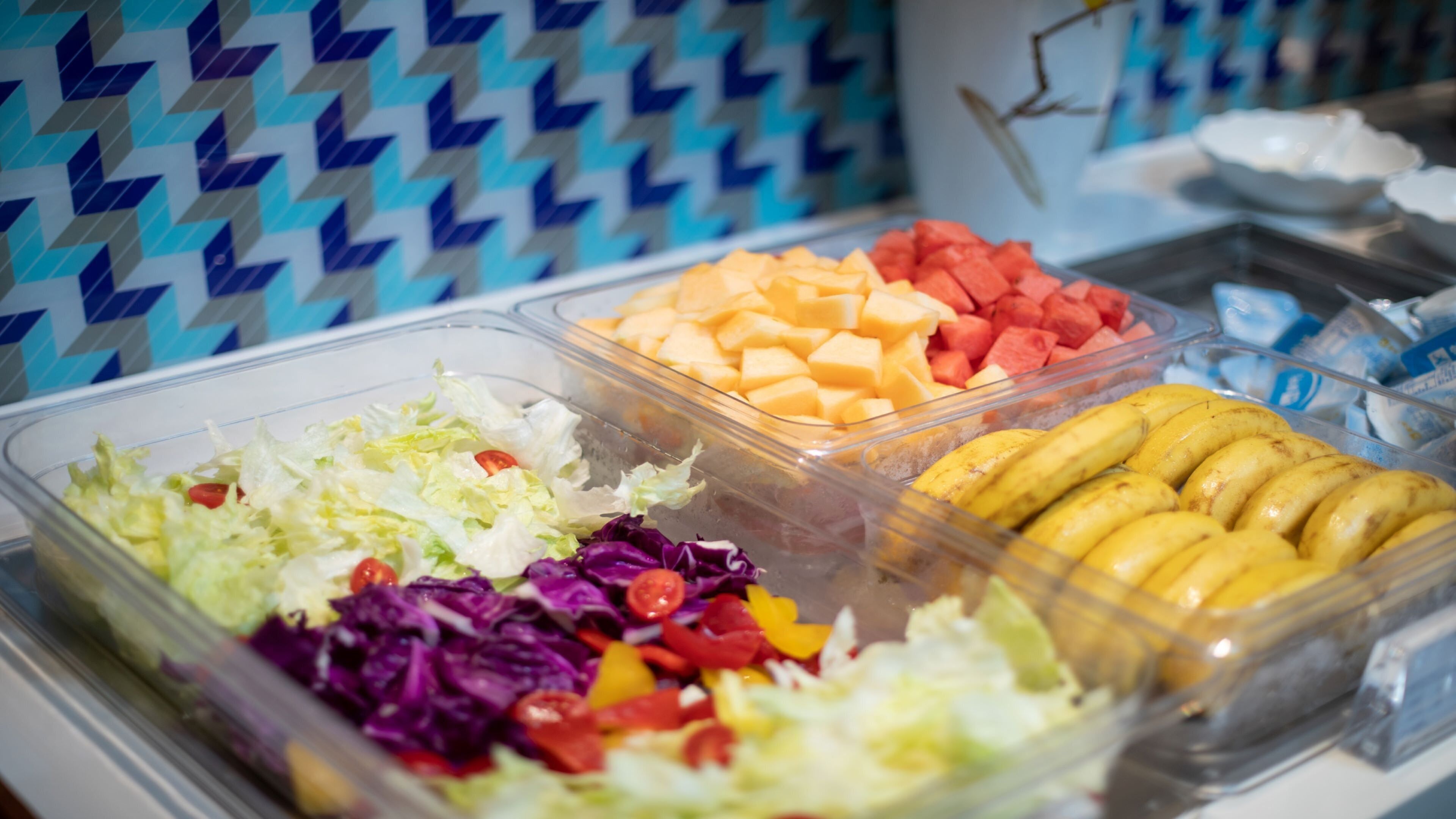 A buffet with various food items including salads, fruits, and bananas.