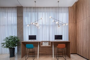 A modern office space with two desks, each with a computer monitor, a small printer, and a potted plant.