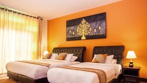 A hotel room with two beds, a large decorative wall piece, and a patterned rug. - Joy's House (Chiang Mai)