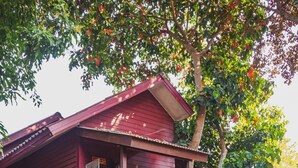 A two-story wooden house with a balcony, surrounded by lush greenery and potted plants. - Joy's House (Chiang Mai)