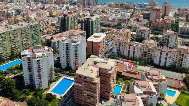 A coastal cityscape with high-rise residential buildings, a clear blue sky, and a visible swimming pool. - Great apartment with pool in Los Boliches (FUENGIROLA)