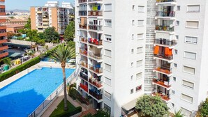 A high-rise building with multiple balconies, a swimming pool, and a lush green garden. - Great apartment with pool in Los Boliches (FUENGIROLA)
