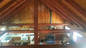 L’intérieur d’un chalet rustique comprend un coin cuisine, des poutres en bois et une mezzanine.
