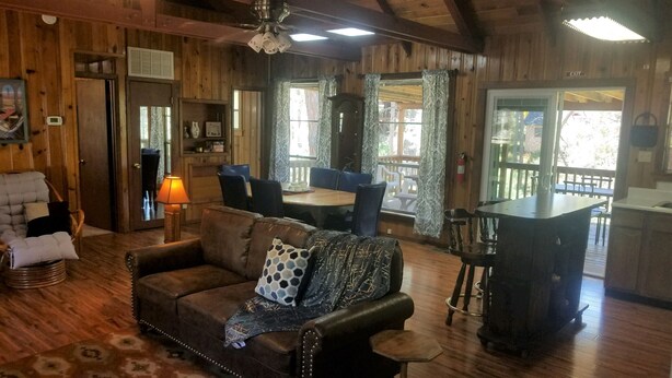 L’intérieur chaleureux d’un chalet comprend un coin repas en bois, un bar et un salon avec un canapé et des fauteuils.