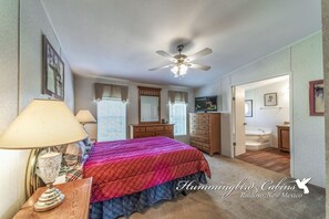 Ein Schlafzimmer mit Bett, Schminktisch, Kommode und Deckenventilator.