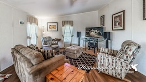 A spacious living room with a sofa, armchairs, a coffee table, and a TV.