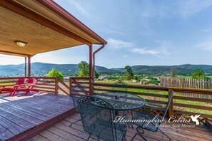 Eine Holzterrasse mit Sitzgelegenheiten im Freien, einer Pergola und Blick auf eine gebirgige Landschaft.