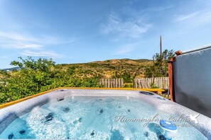 Ein Whirlpool mit Holzterrasse und Blick auf die Hügel.