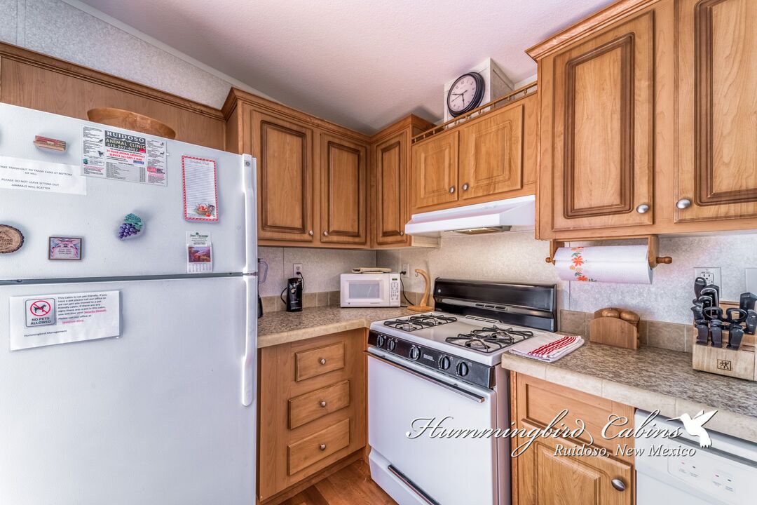 Une cuisine avec des meubles de rangement en bois, un réfrigérateur blanc, une cuisinière et un four à micro-ondes.