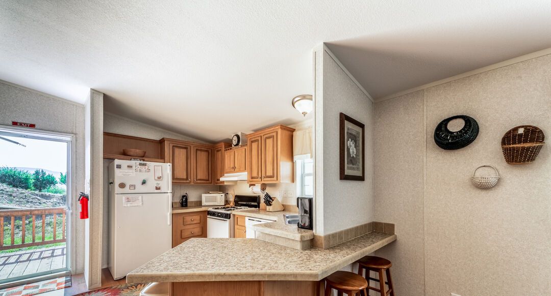 A kitchen with wooden cabinets, a granite countertop, and a bar stool.