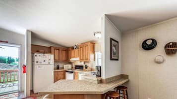 A kitchen with wooden cabinets, a granite countertop, and a bar stool.