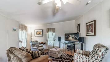 A spacious living room with a sofa, armchairs, a coffee table, and a TV.