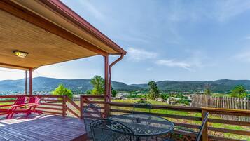 A wooden deck with outdoor seating, a pergola, and a view of a mountainous landscape.