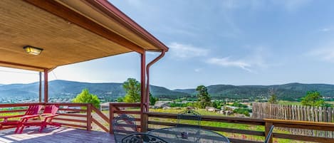 Une terrasse en bois avec des sièges d’extérieur, une pergola et une vue sur un paysage montagneux.