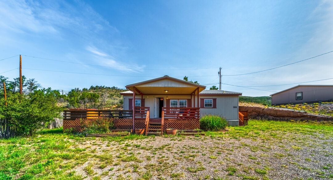 Eine Holzhütte mit einer Holzterrasse, einer Veranda und einem Schotterweg.