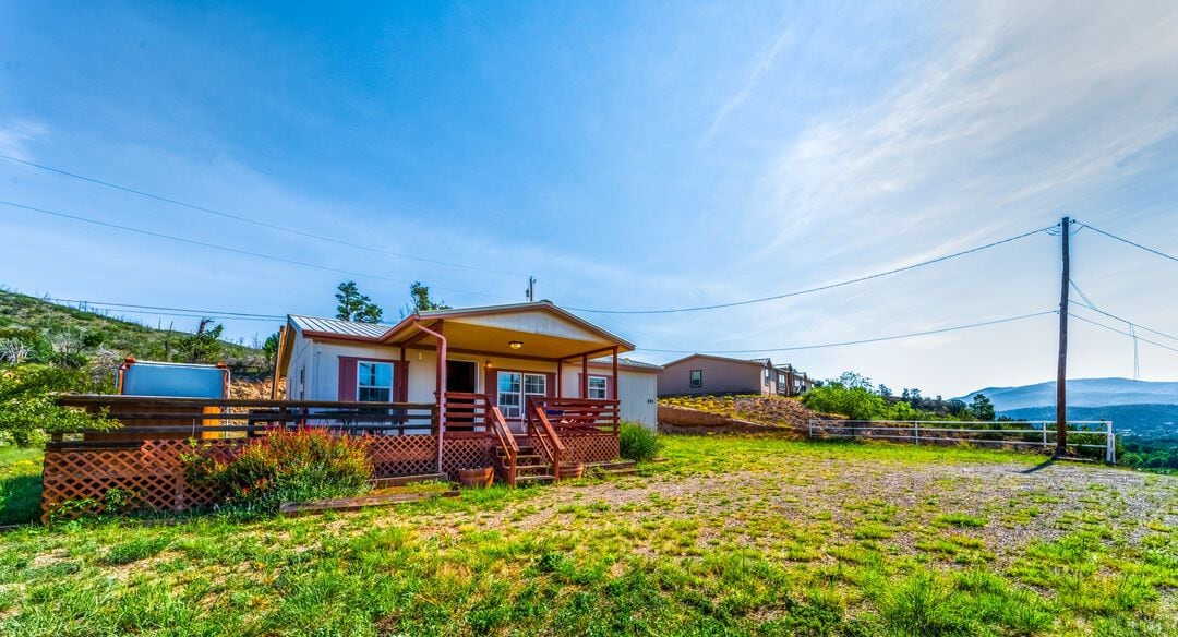 Eine Hütte mit Veranda, einem eingezäunten Garten und freiem Blick auf die umliegende Landschaft.