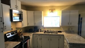 Una cucina con mobili bianchi, un fornello, un lavello e una finestra.