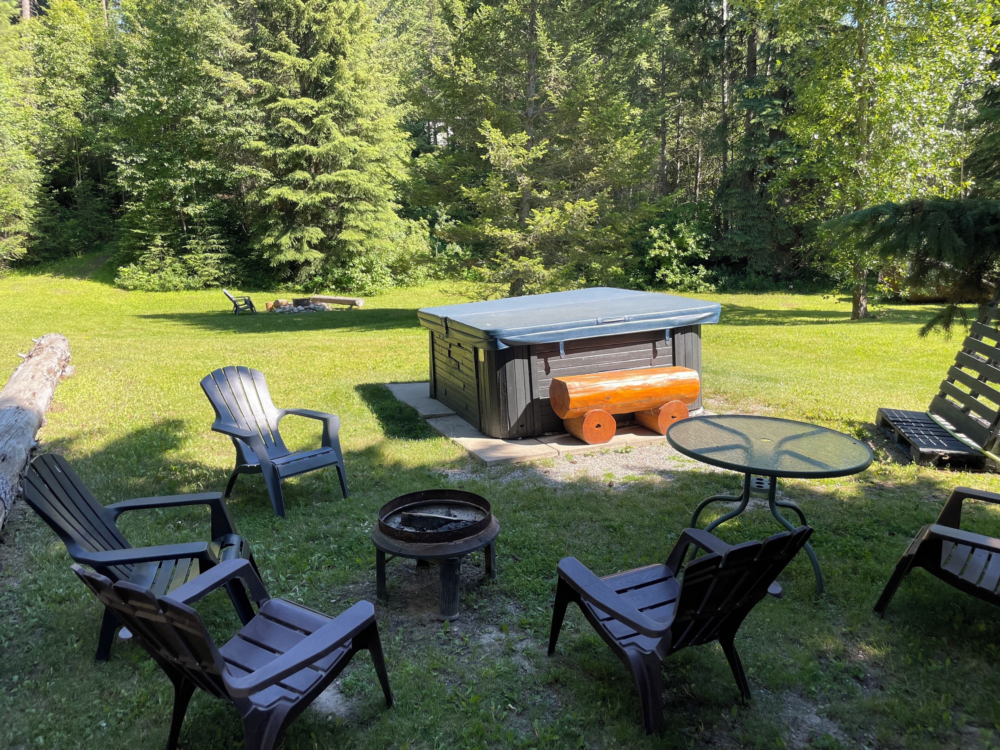 Un espace extérieur aménagé avec des chaises Adirondack, un foyer et un jacuzzi.