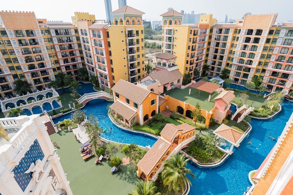 Un hôtel à plusieurs étages doté d’une cour intérieure où se trouve une piscine, le tout entouré d’une végétation luxuriante et de palmiers.