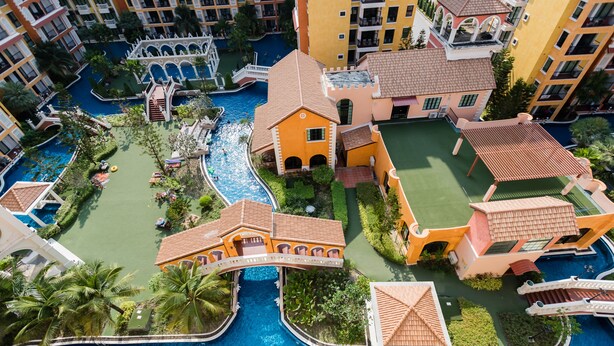 A resort with multiple swimming pools, a bridge, and lush landscaping. - Venetian Signature by GrandisVillas (Pattaya)