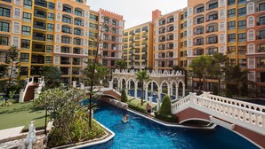 A multi-story hotel with balconies, a swimming pool, and a bridge. - Venetian Signature by GrandisVillas (Pattaya)