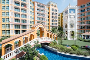 A hotel with multiple balconies, a central courtyard with a pool, and a clock tower.