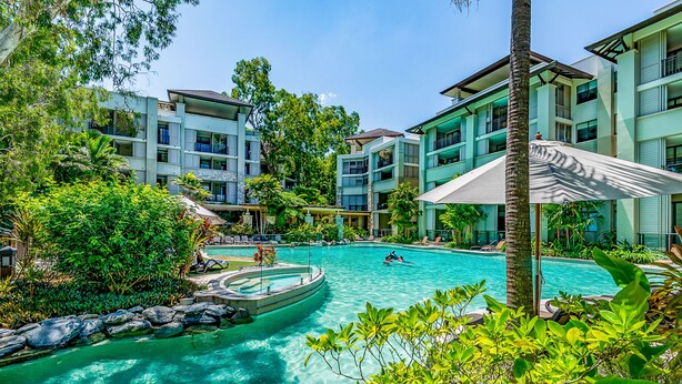 Una piscina rodeada de vegetación exuberante y edificios modernos.