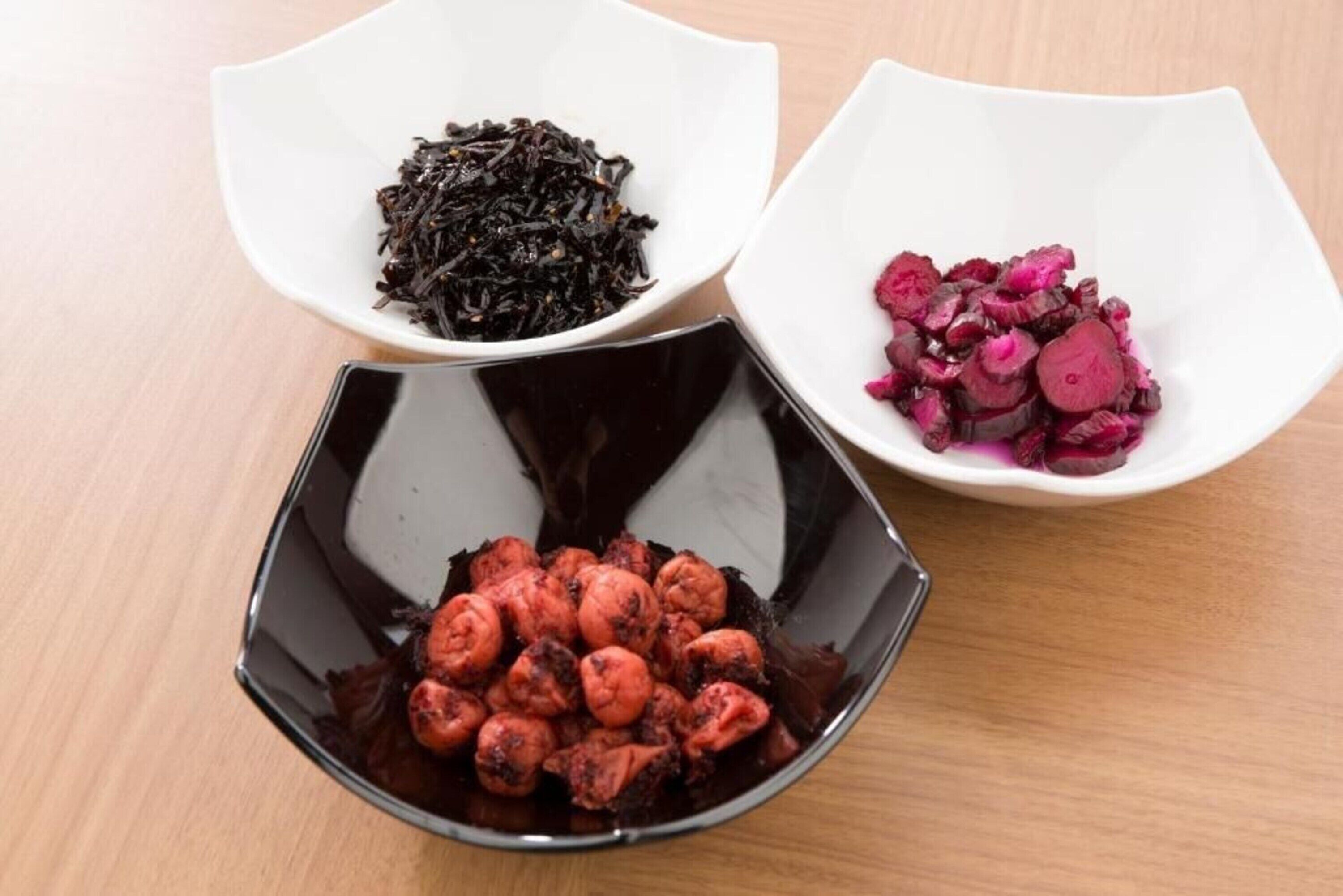 Three bowls containing different food items on a wooden table.
