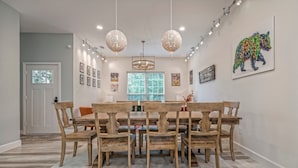 Un comedor con una mesa y sillas de madera, una lámpara de araña y obras de arte en las paredes.