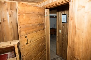 Une porte en bois avec une poignée en métal, une enseigne sur le mur et un aperçu d’une pièce dont le sol est recouvert de carreaux.