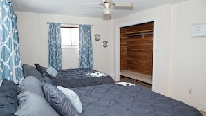 Un dormitorio con dos camas, un ventilador de techo y un armario de madera.
