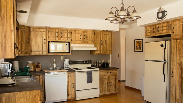 Una cocina con armarios de madera, estufa, refrigerador y microondas.