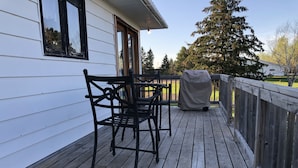 Una terraza de madera con una parrilla cubierta y dos sillas.