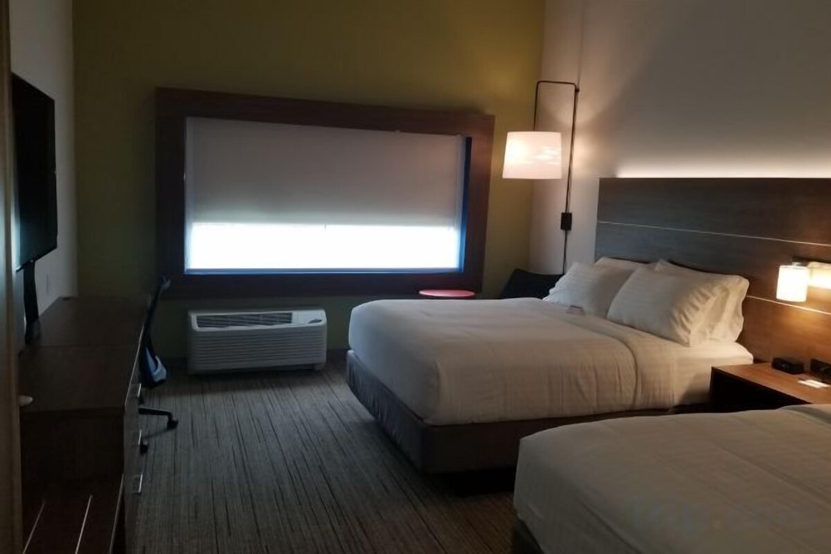 Habitación de hotel con dos camas, un televisor de pantalla plana, un escritorio y una lámpara.