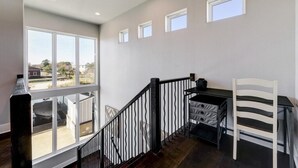 Una habitación amplia con un gran ventanal, una escalera, un escritorio y una silla.