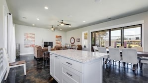 Una cocina amplia con una isla grande, electrodomésticos modernos y un comedor con un ventanal que ofrece vistas.