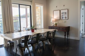 Un coin repas comprenant une grande table, des chaises, une plante en pot, une lampe et un buffet.