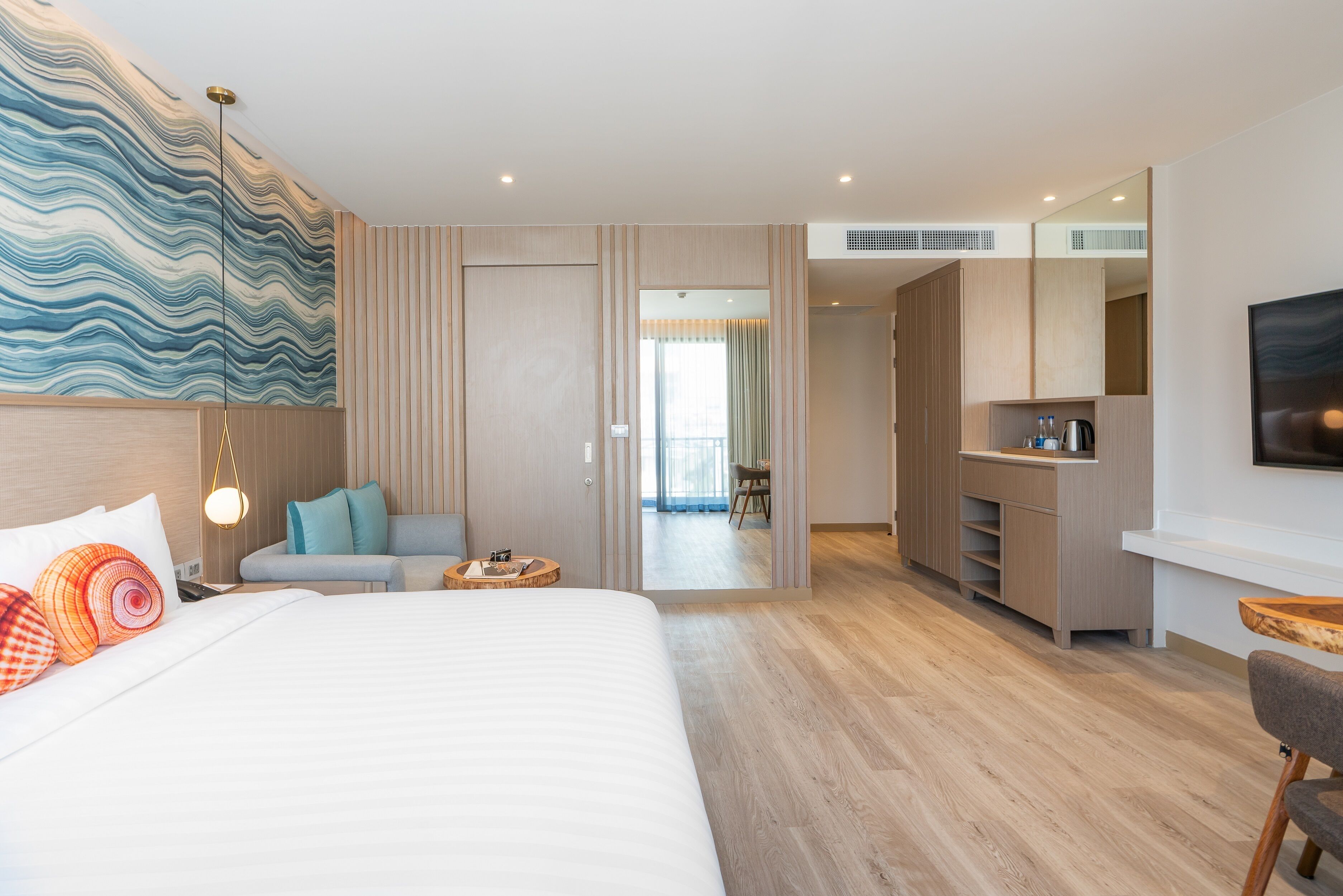 Una habitación de hotel moderna con una cama grande, un sofá, un escritorio y un televisor.