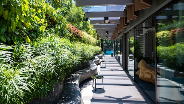 A modern building with a glass facade, a rooftop garden, and a seating area with a sofa. - Maven Stylish Hotel Hua Hin (Hua Hin)