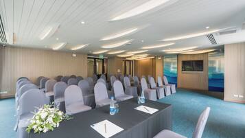 A conference room with rows of chairs, a table with water bottles, and a floral centerpiece.
